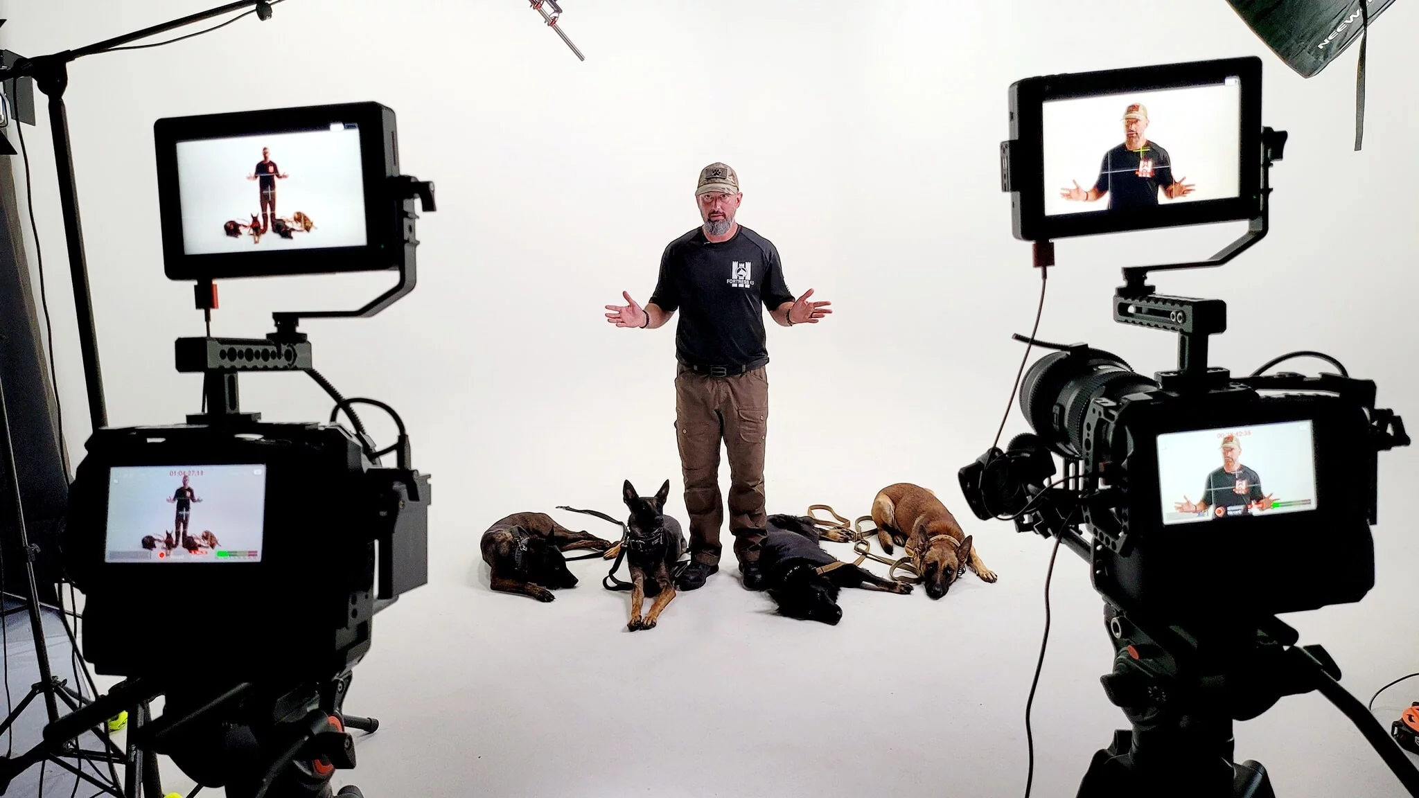 A man standing in front of two dogs and some cameras.
